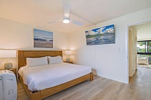 Een slaapkamer met een houten bed, een plafondventilator, twee wandlampen en een groot landschap.'