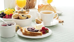 Colazione con pane tostato, muffin, frutti di bosco e caffè.