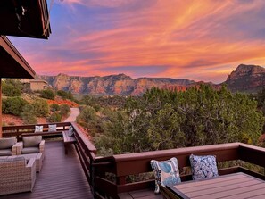 A wooden deck with wicker furniture and a view of a canyon at sunset. - 3-acre Private Designer Villa-borders Forest-forever Views (Sedona)