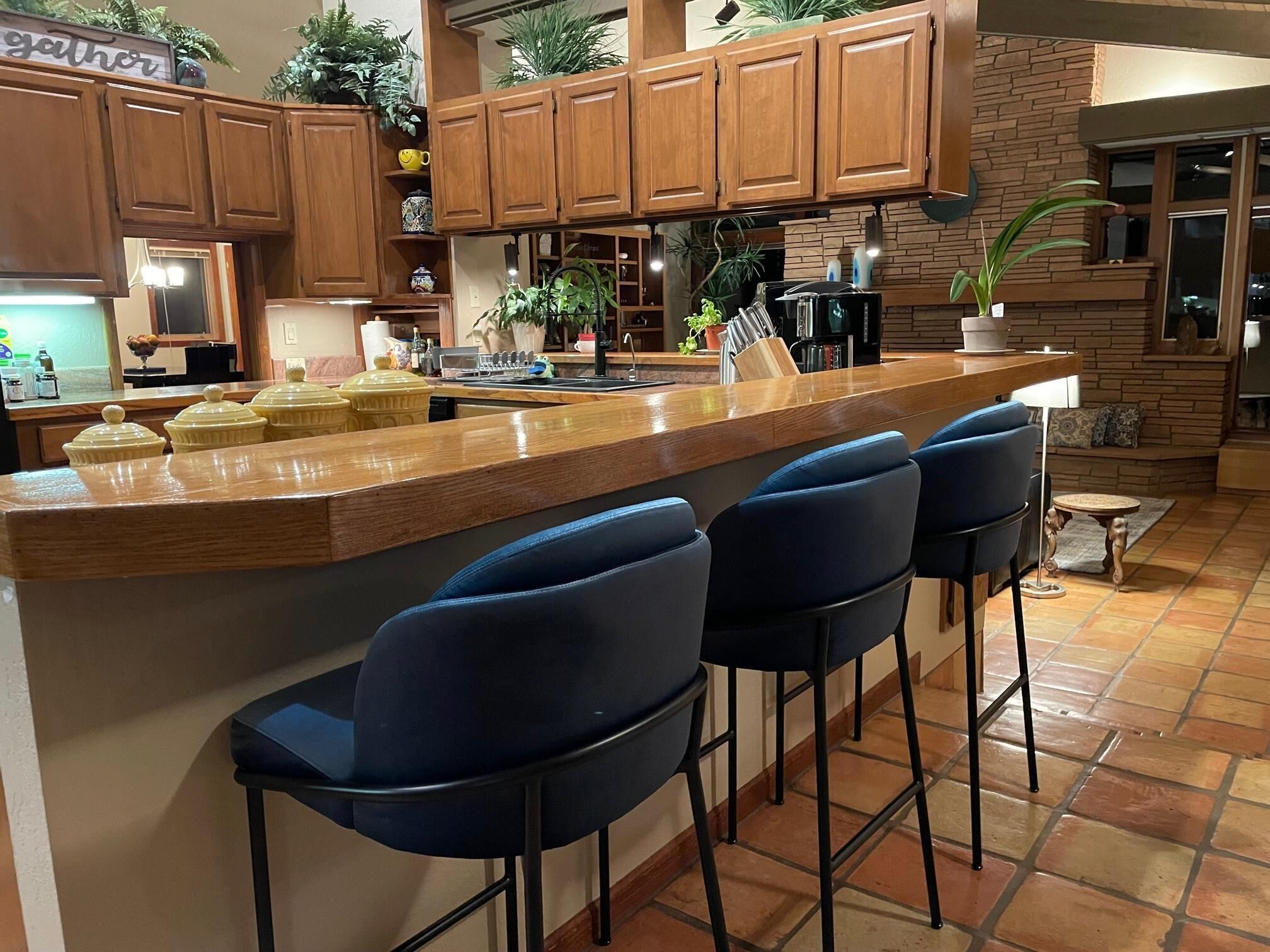 A kitchen with wooden cabinets, a central island with bar stools, and various kitchen appliances.