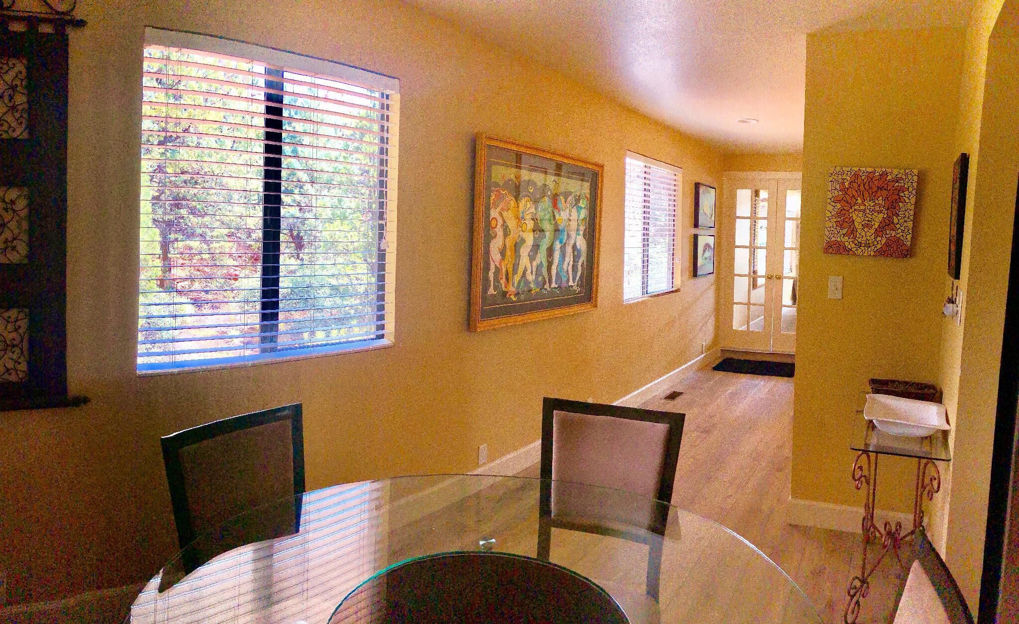 Un coin repas avec une table en verre, des chaises et un tableau accroché au mur.