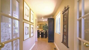 A hallway with framed pictures on the walls, a dining area in the background, and a large decorative mirror. - Sedona Forest Villa Land Nature Lover S Private Paradise (Sedona)