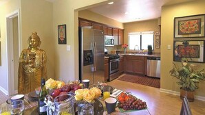 A modern kitchen with stainless steel appliances, wooden cabinets, and a dining area with a Buddha statue. - Sedona Forest Villa Land Nature Lover S Private Paradise (Sedona)