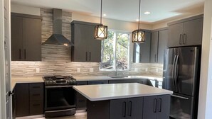 A modern kitchen with dark cabinetry, a stainless steel refrigerator, a built-in oven, and a large island. - Designer View Villa-rooftop 360 View Deck-hot Tub (Sedona)