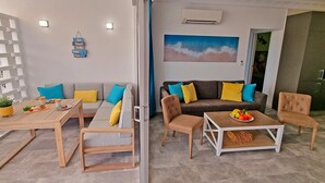 Ein modernes Wohnzimmer mit einer Couch, Sesseln, einem Couchtisch und einem Esstisch.