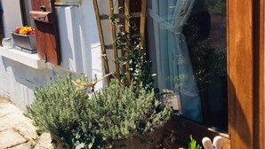 A wooden ladder leaning against a wall, a potted plant with green foliage, and a small rabbit figurine on a tiled surface. - 2 Rue des Sources Fraiches (Cussac)