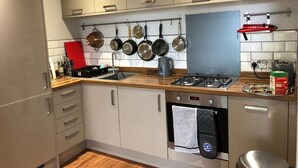Une cuisine moderne avec des armoires blanches, un plan de travail en bois et une cuisinière en acier inoxydable.