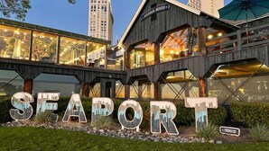 A waterfront hotel with a prominent 'SEAPORT' sign, outdoor seating, and a view of the city skyline. - Ideally located near San Diego’s Top Tourist Attractions (SAN DIEGO)