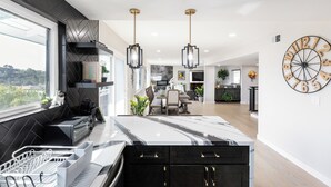 A modern kitchen with a large island, pendant lighting, and a clock on the wall. - Ideally located near San Diego’s Top Tourist Attractions (SAN DIEGO)