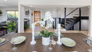 A dining area with a wooden table set for four, surrounded by white candles and a potted orchid. - Ideally located near San Diego’s Top Tourist Attractions (SAN DIEGO)