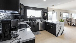 A modern kitchen with dark cabinetry, a marble countertop, and a built-in island. - Ideally located near San Diego’s Top Tourist Attractions (SAN DIEGO)