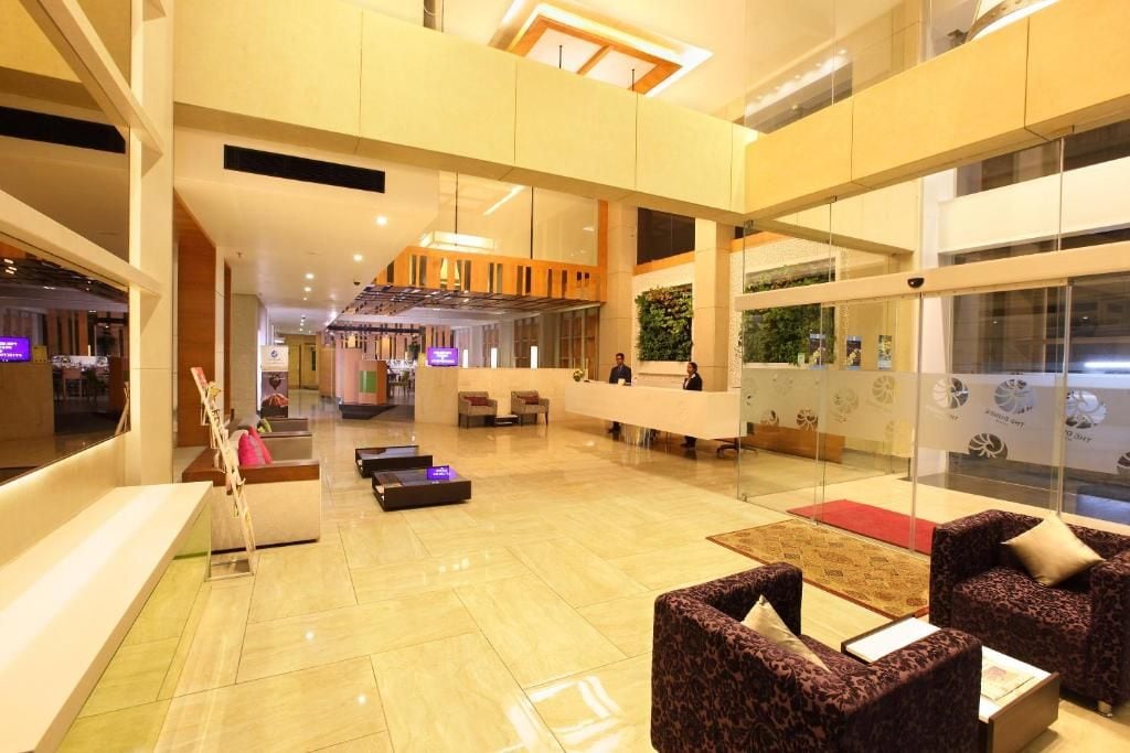 A spacious lobby with a reception desk, seating areas, and a modern interior design.