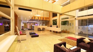A spacious lobby with a reception desk, seating areas, and a modern interior design.