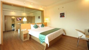 A hotel room with a bed, bedside table, chair, and a TV.