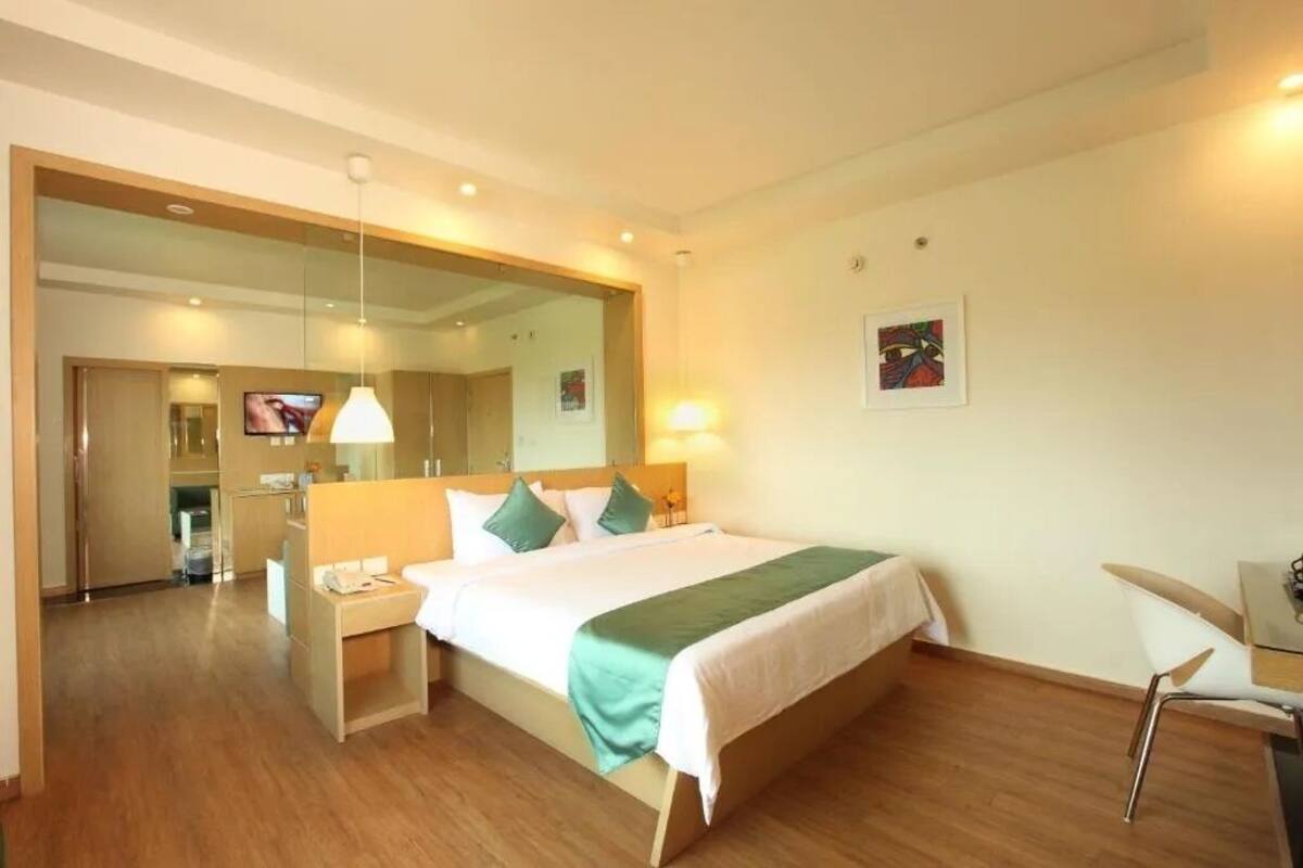 Ein Hotelzimmer mit Bett, Nachttisch, Sessel und Fernseher.