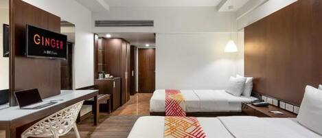 A hotel room with a bed, a desk with a laptop, a TV mounted on the wall, and a wardrobe.