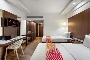 Habitación de hotel con cama, escritorio con ordenador portátil, televisor montado en la pared y armario.