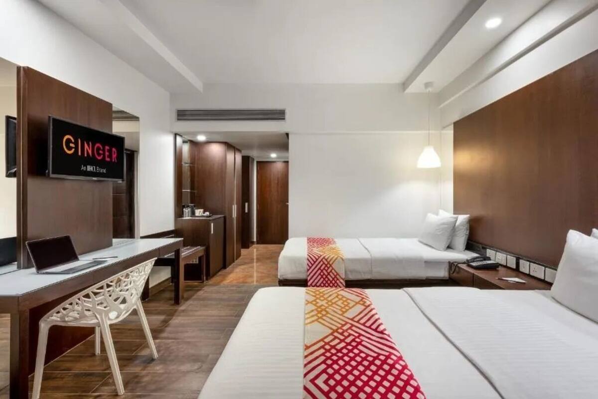 Ein Hotelzimmer mit Bett, Schreibtisch mit Laptop, Wand-Fernseher und Kleiderschrank.