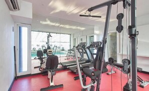 Ein Fitnessstudio mit Laufbändern, Gewichten und einem großen Spiegel.