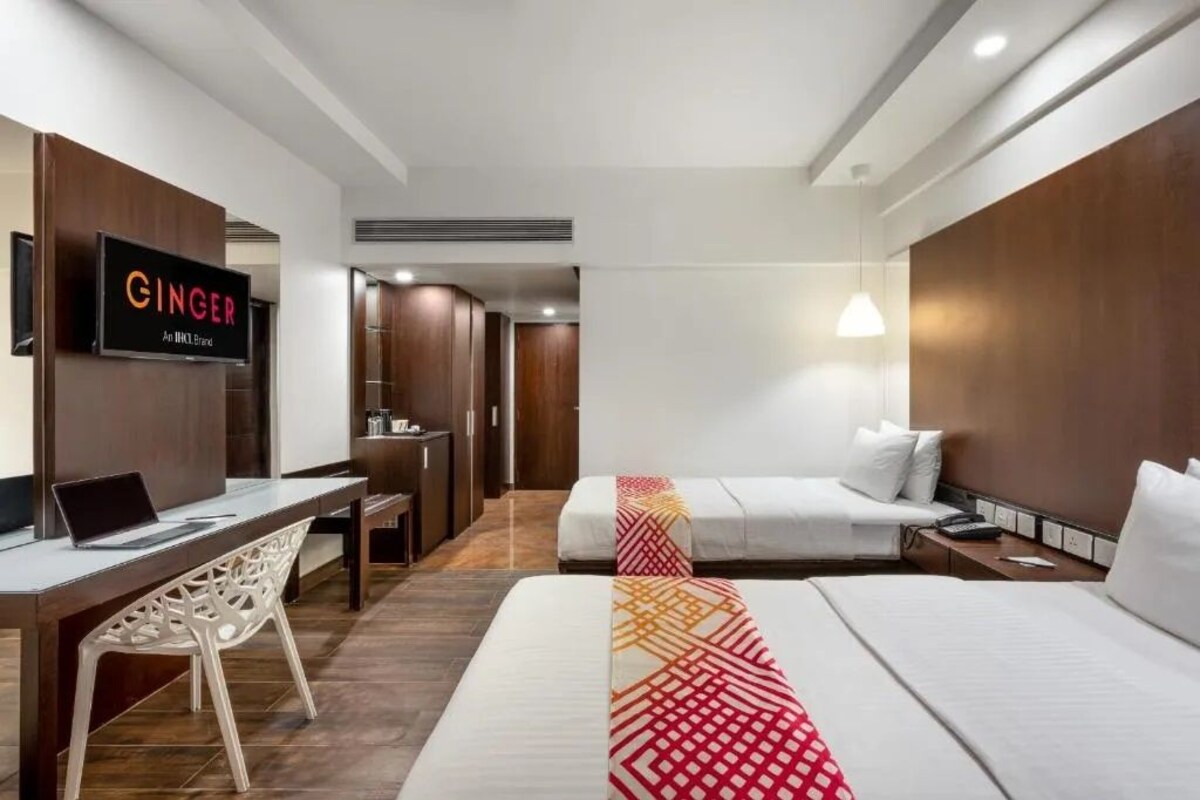 Habitación de hotel con cama, escritorio con ordenador portátil, televisor montado en la pared y armario.