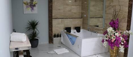 Un baño moderno con una bañera grande, un espejo, un lavabo y una planta en maceta.