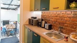 A kitchen with a brick wall, stainless steel appliances, and a wooden countertop.