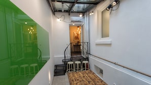 A narrow hallway with a wooden bench, stools, and a staircase leading to an upper floor.