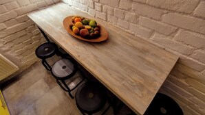 A wooden table with a fruit bowl and three stools.