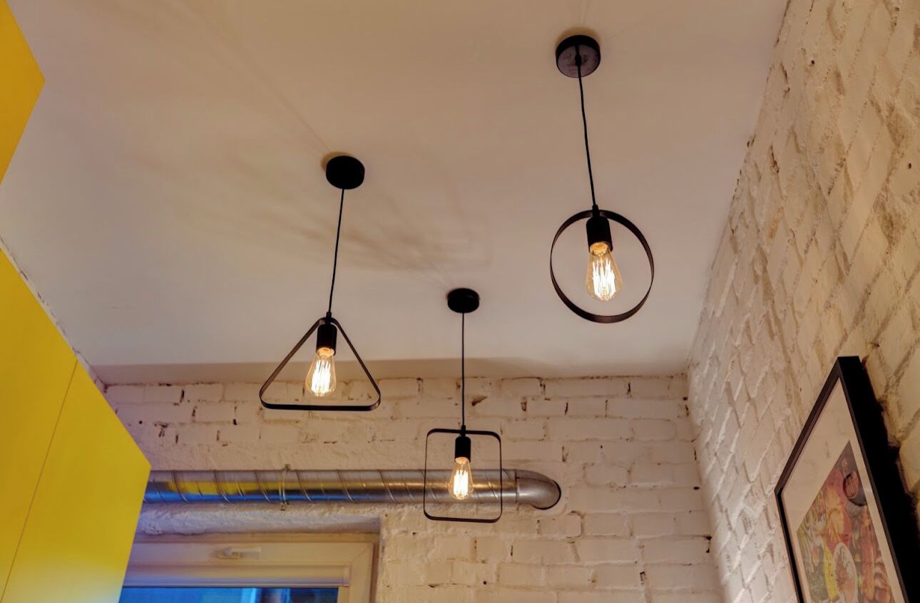 A ceiling with exposed ductwork and three hanging pendant lights.