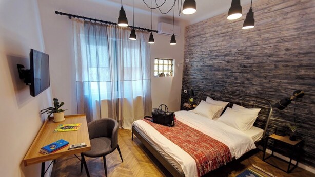 A modern bedroom with a bed, desk, chair, and a TV.