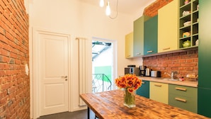A kitchen with a wooden table, a vase of flowers, and green cabinets.