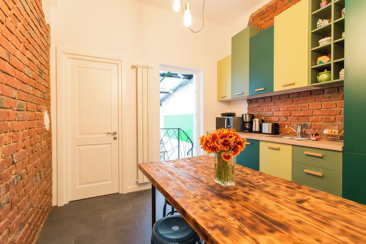 A kitchen with a wooden table, a vase of flowers, and green cabinets.