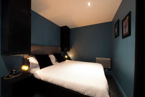 A modern bedroom with a large bed, dark walls, and minimalistic decor.