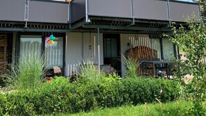 Una casa moderna de dos pisos con un balcón, un porche cubierto y un jardín.
