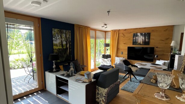 Una sala moderna con un sofá, televisión y un comedor con mesa y sillas.