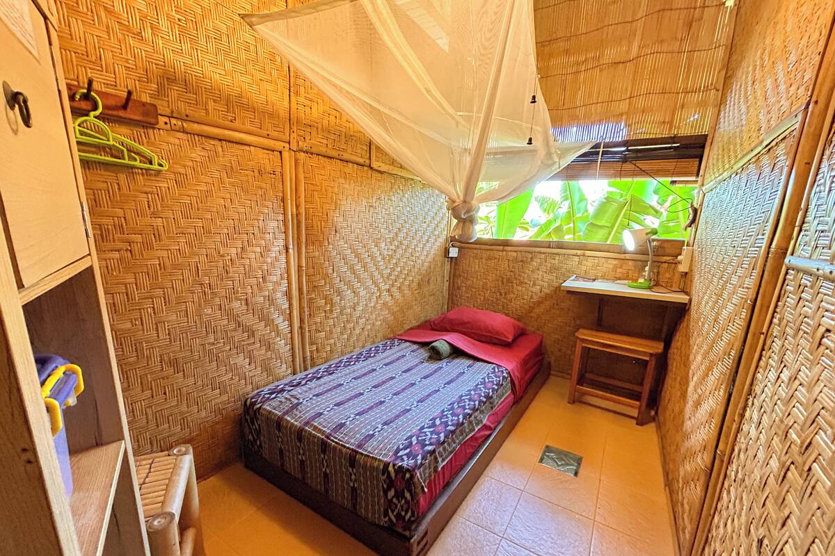 Una habitación pequeña y privada con cama, escritorio y silla.