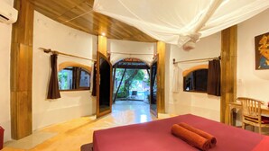 Una habitación con cama, suelo de madera, ventana con cortinas y vistas a un espacio exterior.