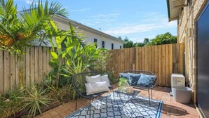 A patio with a patterned rug, two chairs, and a small table.