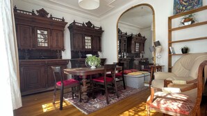A dining area with a wooden table, chairs, and a mirror. - Maison au Calme et au Vert au Cœur du Centre Ville (Vincennes)