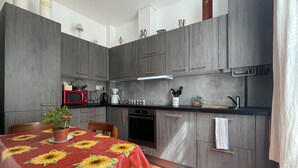 A compact kitchen with grey cabinets, a red microwave, a coffee maker, and a sink. - Maison au Calme et au Vert au Cœur du Centre Ville (Vincennes)