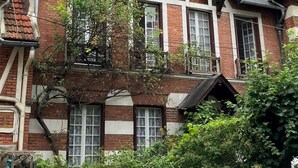 A two-story building with a brick facade, large windows, and a sloped roof. - Maison au Calme et au Vert au Cœur du Centre Ville (Vincennes)