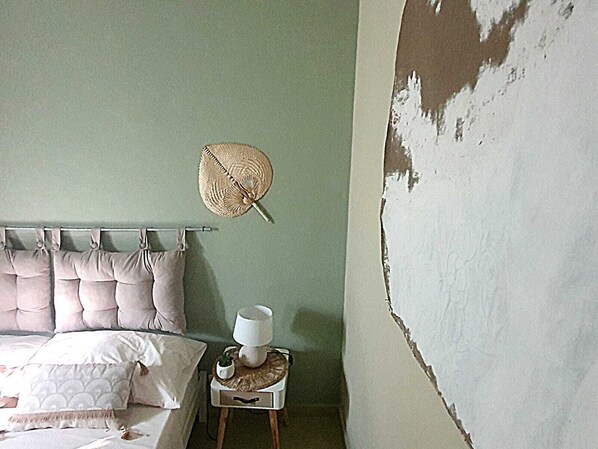 A bedroom with a bed, pillows, a bedside table with a lamp, and a wall with peeling paint. - ArtHouse Santa Marinella B&B (Beach) (Santa Marinella)