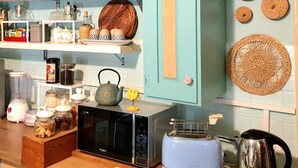 A kitchen with a microwave, toaster, and various kitchen items on shelves.