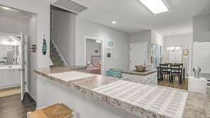 A modern kitchen with granite countertops, a dining area with a table and chairs, and a staircase leading to another level. - TB 93C Wonderful 3/bed 2/bath Garden home in True Blue (Pawleys Island)