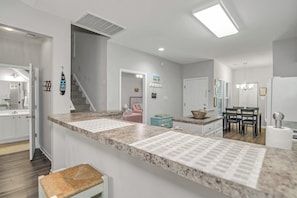 A modern kitchen with granite countertops, a dining area with a table and chairs, and a staircase leading to another level.