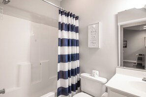 Une salle de bain avec un rideau de douche, des toilettes, un lavabo et une citation encadrée au mur.