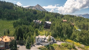 A large, modern house with multiple sections, surrounded by dense forest and mountains. - Spacious Mountain Manor with 9 bedrooms, 11 baths and Hot Tub (Crested Butte)