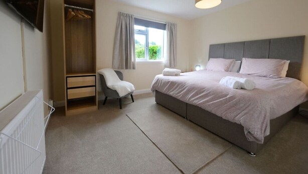 A bedroom with a bed, a chair, a wardrobe, and a window.