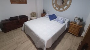 A bedroom with a bed, a wooden dresser, a chair, a nightstand, and a wall decoration. - la Cordobesa (Priego de Córdoba)