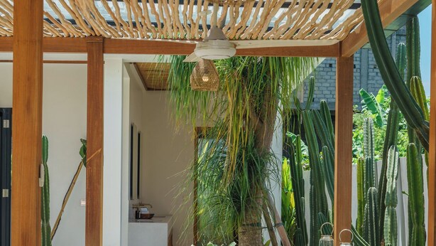 An outdoor seating area with a wooden pergola, cushioned benches, and a table. - Villa Air - 2BR Villa in Pererenan (Canggu)